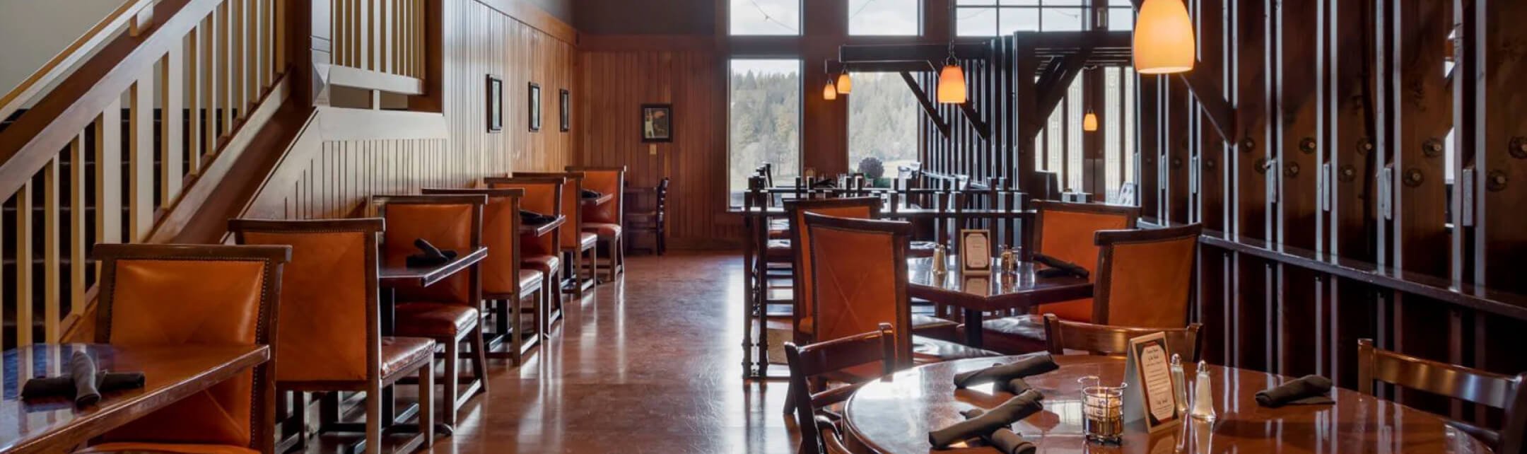 Dining space at a restaurant, multiple empty tables and chairs fill the space.