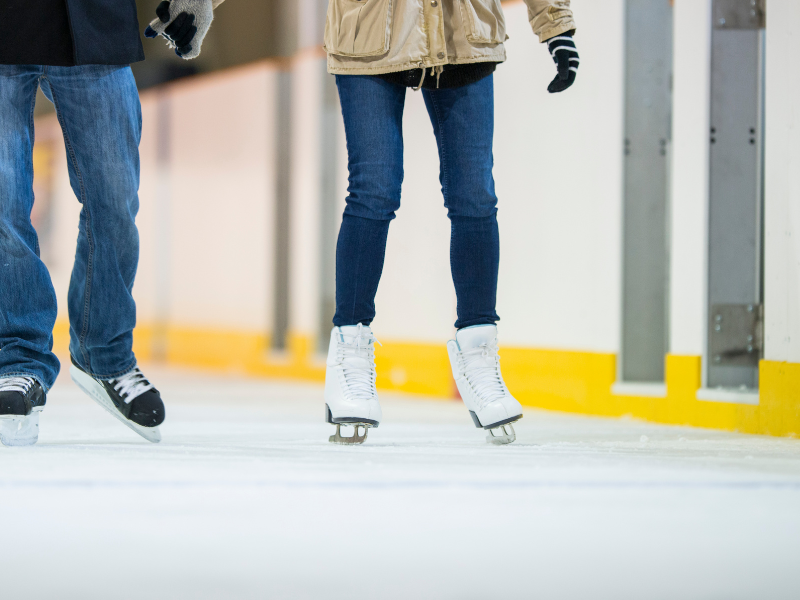 A couple ice skating in an indoor rink.