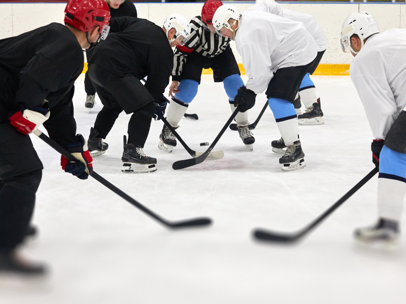 A group of men playing ice hockey in an indoor ice rink.