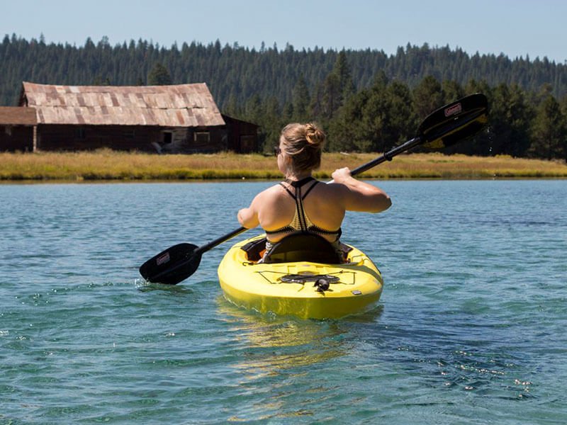 A woman paddling in a single kayak on the water.