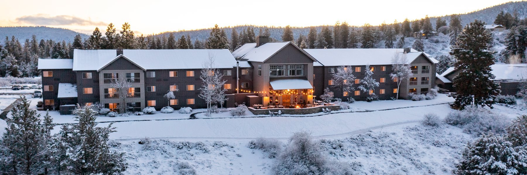 Aerial view of the lodge during the winter with snow covered rooftops and grounds.