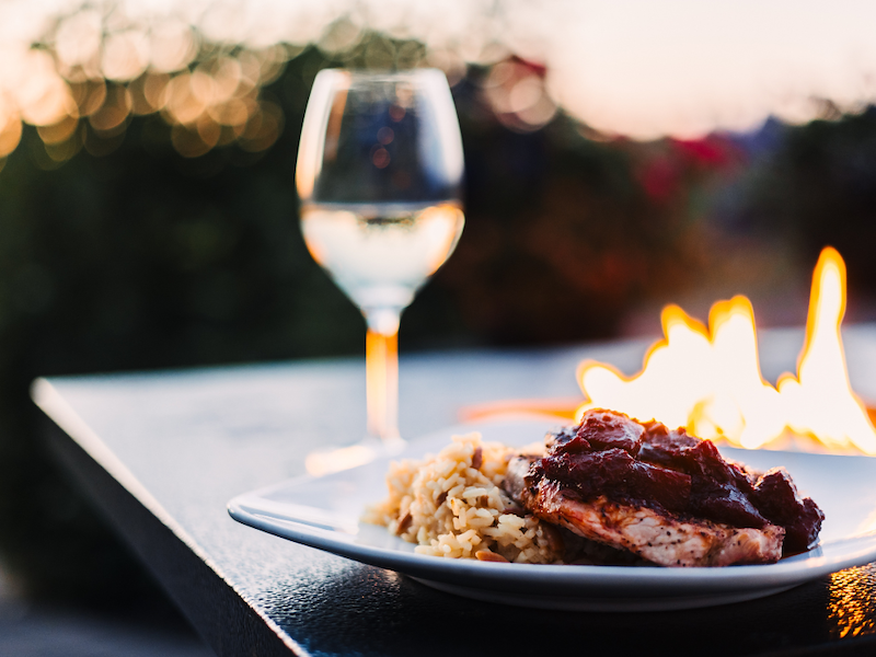 A plate of food next to a firepit and a glass of water.