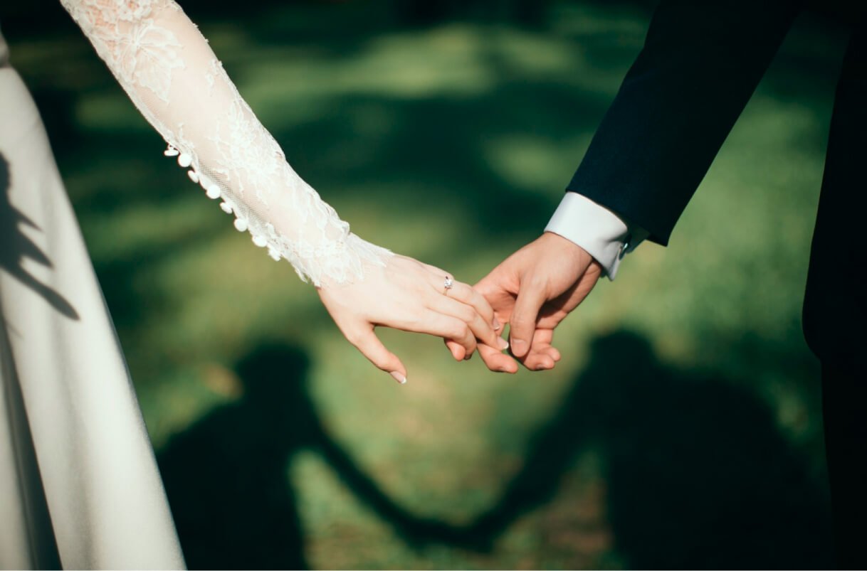 A close up of a bride and groom holding hands