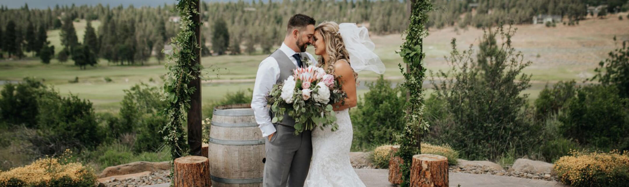 A bride and groom facing each other with their foreheads touching, standing next to an alter at their wedding.
