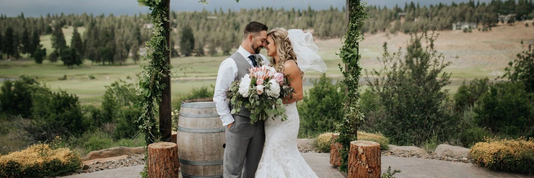 A bride and groom facing each other with their foreheads touching, standing next to an alter at their wedding.