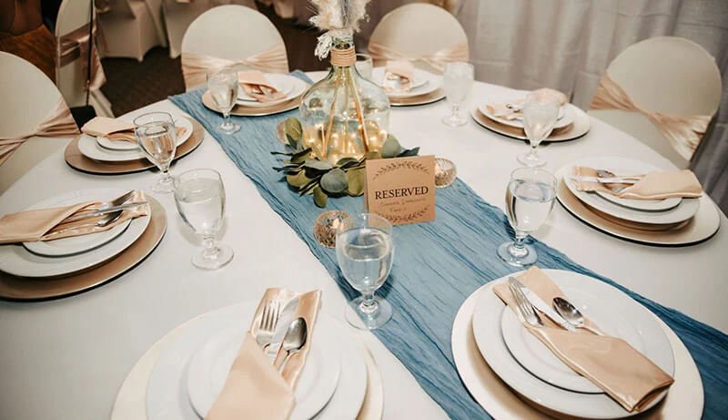 a table adorned with a blue runner and a reserved sign, likely part of the dining area at a wedding.