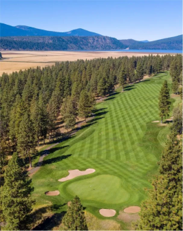An aerial view of the golf course at Running Y Resort in the summertime, with the Cascade Mountain range in the background.
