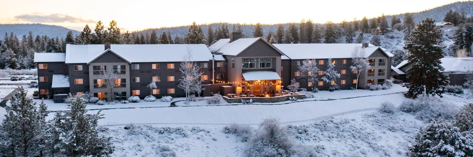 Aerial view of the lodge during the winter with snow covered rooftops and grounds.
